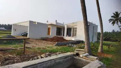 a house under construction with a palm tree at Glass house in Pollāchi