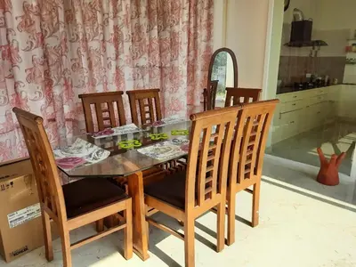 a dining room with a table with chairs and a mirror at Glass house in Pollāchi