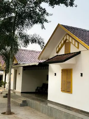 a white house with yellow windows and a palm tree at SRK luxe resort