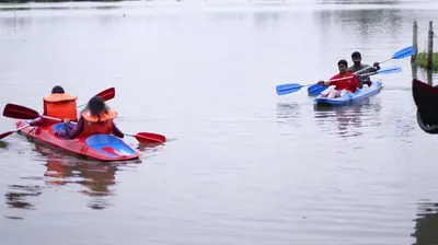 three children are riding in kayaks on the water at Atharvam Resort in Cherai Beach