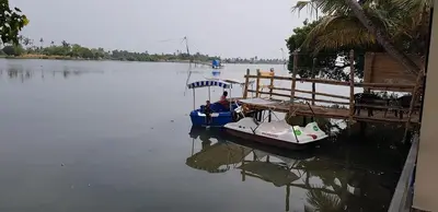 a small boat parked next to a dock on the water at Atharvam Resort in Cherai Beach