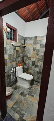 a bathroom with a toilet and a stone wall at Hayden in Kakkadampoyil