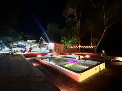 a swimming pool with lights in a yard at night at The Multi Gen Retreat at gaya3farms in Parli