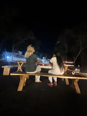 two people sitting on a wooden bench at night at The Multi Gen Retreat at gaya3farms in Parli