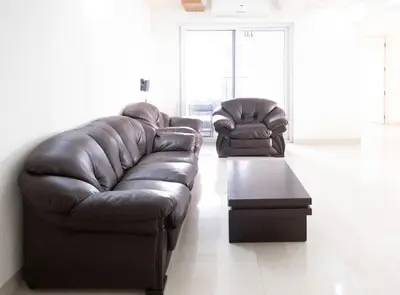 a living room with a leather couch and a coffee table at 2BHK with Pool and Rooftop at the Centre of Kozhikode in Kozhikode