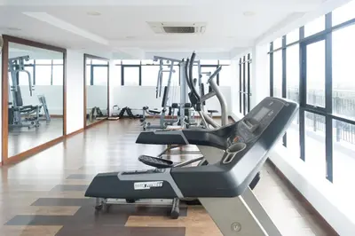 a gym with cardio equipment in a large room with windows at 2BHK with Pool and Rooftop at the Centre of Kozhikode in Kozhikode