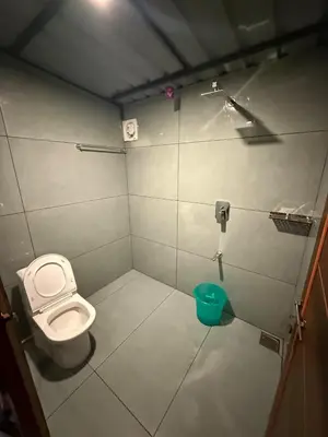 a small bathroom with a toilet and a bucket at Boche LuxCamp 1000 Acre in Wayanad