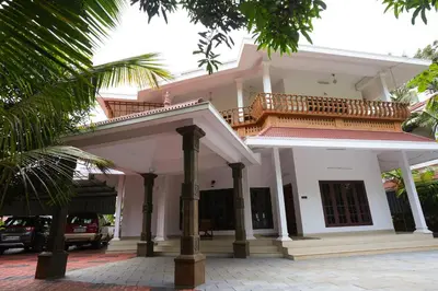 a white house with a balcony on top of it at Guruvayur Nature Homestay in Kunnamkulam