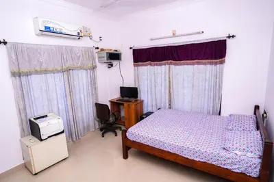 a bedroom with a bed and a tv and curtains at Guruvayur Nature Homestay in Kunnamkulam