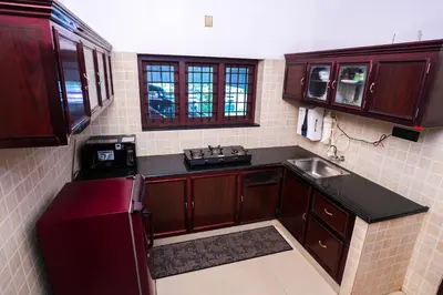 a kitchen with wooden cabinets and a sink at Guruvayur Nature Homestay in Kunnamkulam