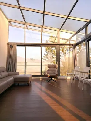 a living room with a couch and chairs and windows at A private room in a luxury villa- The Water's Edge in Kotagiri