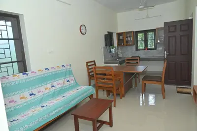 a living room with a bench and a dining room at Nisarga Greens in Chittūr