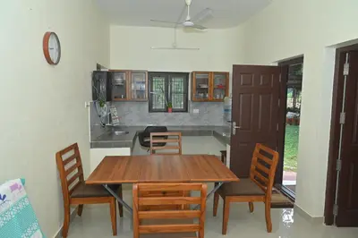 a dining room with a wooden table and chairs at Nisarga Greens in Chittūr