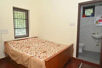 a bedroom with a bed and a bathroom with a sink at Nisarga Greens in Chittūr