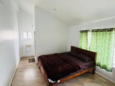 a bedroom with a bed and a window with green curtains at Majestry Cottage in Ooty