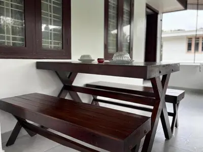 a wooden table and a bench in a room at Ravi's homestay in Cochin