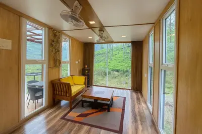 a living room with a yellow couch and a table at The Leafy Nook Container Stay- 360 degree Tea Plantation near Ooty in Coonoor