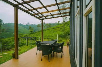 a table and chairs on a porch with a view at The Leafy Nook Container Stay- 360 degree Tea Plantation near Ooty in Coonoor