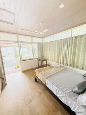 a bedroom with a bed and a large window at Greenwoods Mist Villa in Munnar