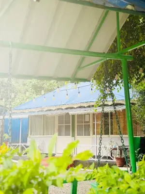 a swing in front of a house with a blue roof at Greenwoods Mist Villa in Munnar