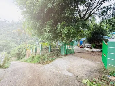 a dirt road with a fence and a tree at Greenwoods Mist Villa in Munnar
