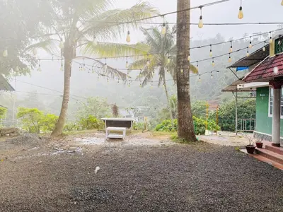 a picnic table in front of a house with palm trees at Greenwoods Mist Villa in Munnar