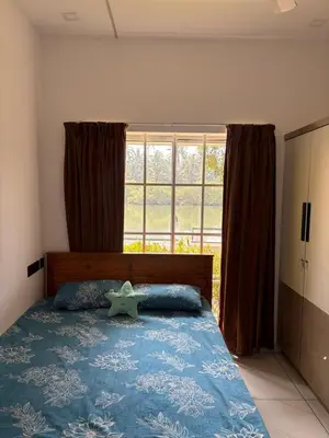 a bedroom with a bed with a large window at Serene riverside retreat in Kozhikode