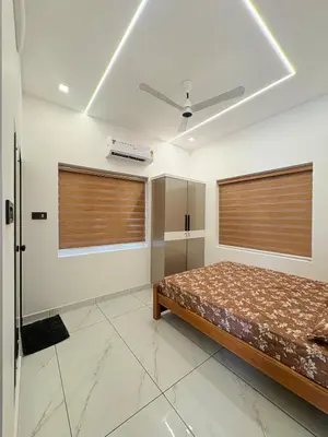 a bedroom with a bed and two windows at Serene riverside retreat in Kozhikode