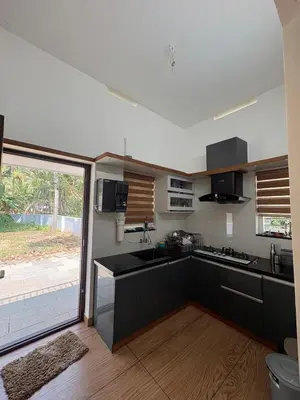 a kitchen with black cabinets and a large sliding glass door at Serene riverside retreat in Kozhikode