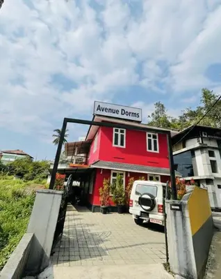 a red building with a van parked in front of it at Avenue Dorms in Kalpetta
