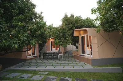 a patio with tables and chairs under trees at Bougain Villa Hilltreat in Muthalamada