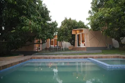 a swimming pool in front of a house with trees at Bougain Villa Hilltreat in Muthalamada