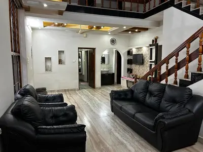 a living room with black leather furniture and a staircase at Metro Bliz in Alwaye
