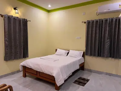 a bedroom with a bed with white sheets and black curtains at Rivora Retreat in Nanjangūd