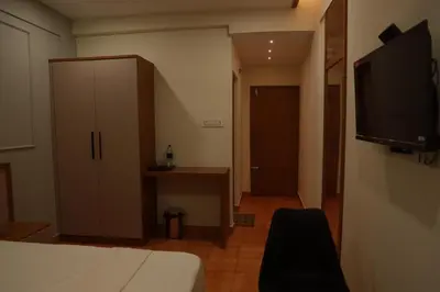 a room with a bed and a cabinet and a television at Amani Residency Kannur in Kannur