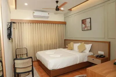 a bedroom with a bed and a table and a chair at Amani Residency Kannur in Kannur