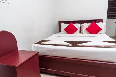 a bedroom with a bed with red pillows and a chair at Wayanad home stay in Vythiri
