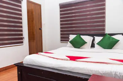 a bedroom with a large bed with green and red pillows at Wayanad home stay in Vythiri