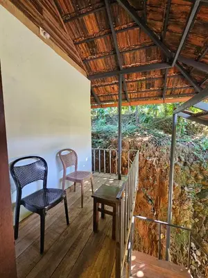 a porch with two chairs and a table and chairs at Falcon by wayanora in Padinjarathara