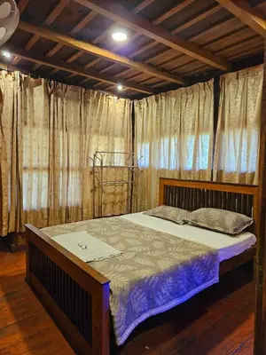 a large bed in a room with curtains at Falcon by wayanora in Padinjarathara