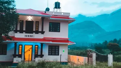 a small white house with a bright orange door at Dew drops Marayoor in Kanthalloor