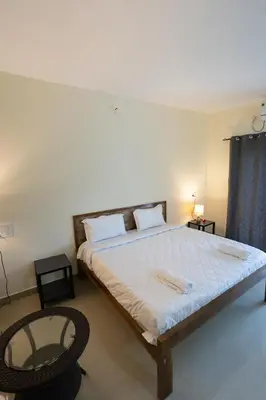 a bedroom with a large bed and a glass table at Bougain Villa in Madikeri