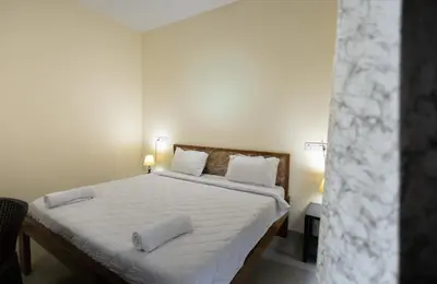 a bedroom with a bed with white sheets and pillows at Bougain Villa in Madikeri