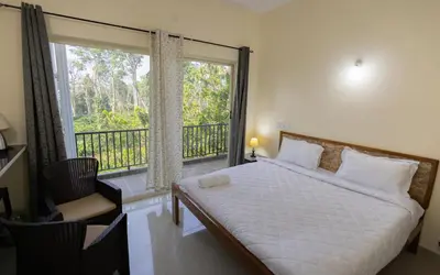 a bedroom with a bed and a balcony with a window at Bougain Villa in Madikeri