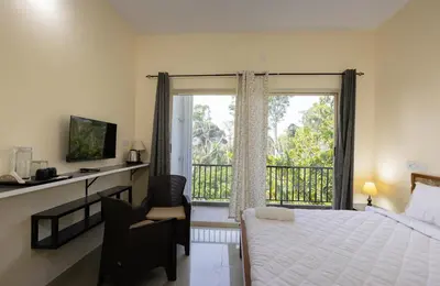 a bedroom with a bed and a window with a balcony at Bougain Villa in Madikeri
