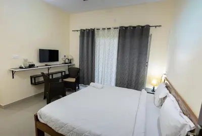 a bedroom with a bed and a desk and a television at Bougain Villa in Madikeri