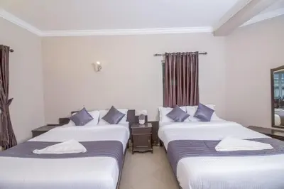 three beds in a hotel room with blue pillows at Mounts shelts in Munnar