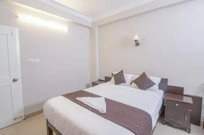 a bedroom with a large white bed with a night stand at Mounts shelts in Munnar