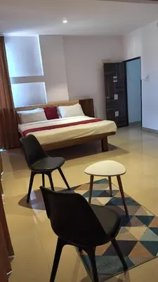 a bedroom with a bed and two chairs and a table at Hemara suites