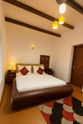 a bedroom with a large white bed with red pillows at Secret Escape Heritage Bungalow in Ooty